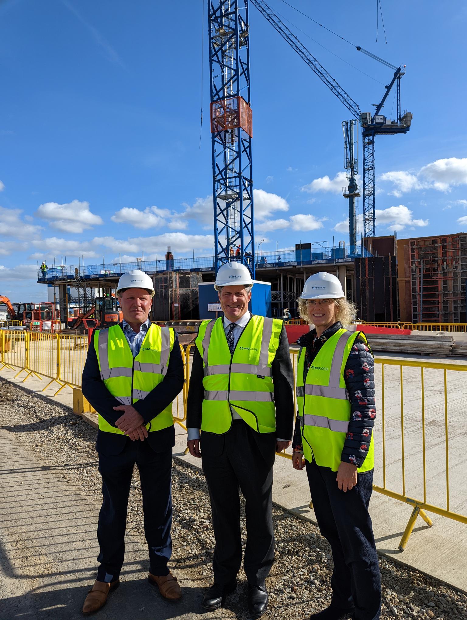 Three Prologis UK team members stand in front of a construction site