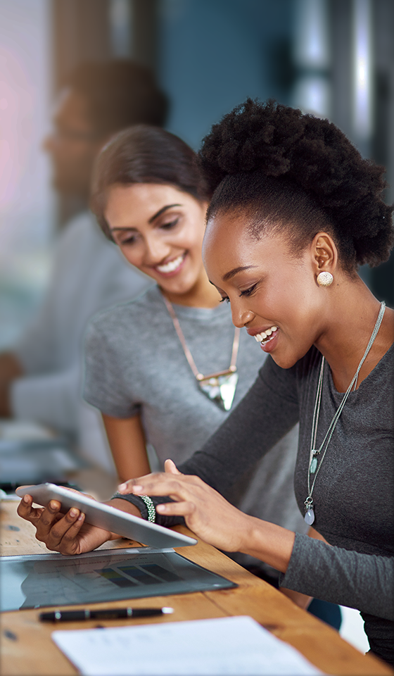 Two women smiling and looking at an iPad