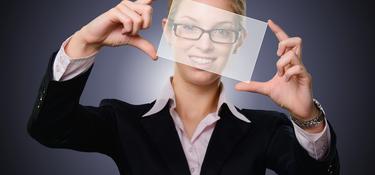 A woman holding up a piece of glass and looking through it