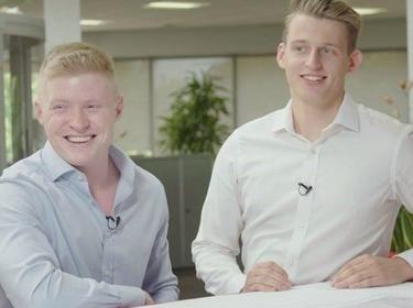 Two men in an office smiling at the camera