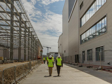 Two people walking on the sidewalk between two buildings