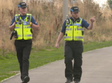 Two men walking down a road with security gear